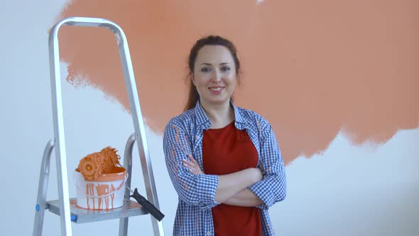 Singleton Lifestyle Concept. Young Happy Woman Paints Her Walls Orange with a Roller