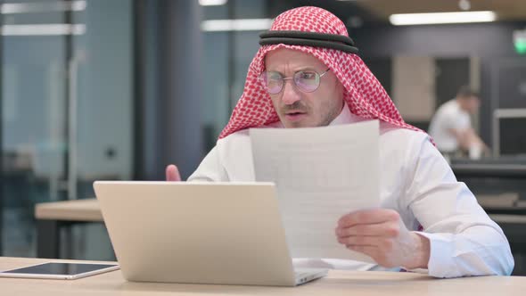 Middle Aged Arab Man with Laptop Reacting to Loss Documents