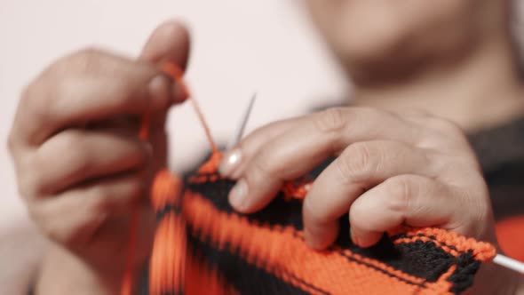 Woman's hands doing knit work tie-up hand work with red and black wool.