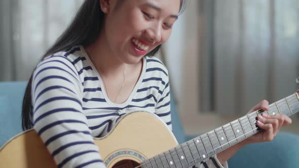 Close Up Of Asian Woman Composer With A Guitar Celebrating For Finishing Composing Music On Paper At