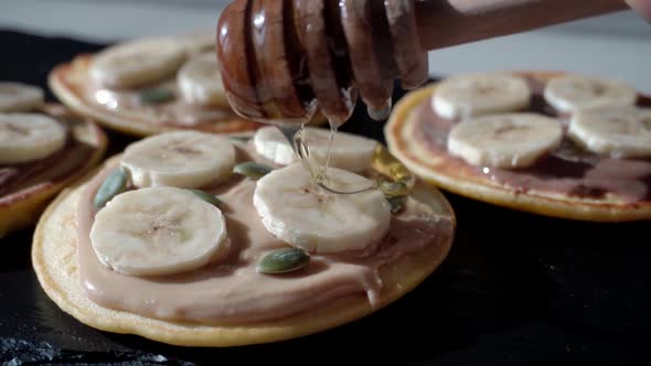 Tasty and sweet Children's breakfast. Honey dripping down on pancakes with fruits Banana on top.