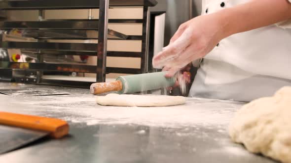 Chef is preparing pastry dough, baking bakery food on a stainless steel table.