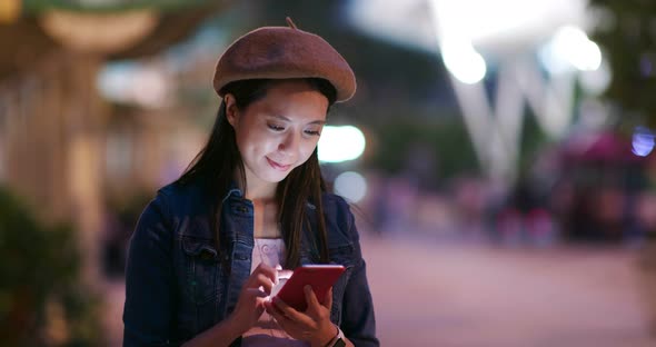 Young woman check on mobile phone in city at night