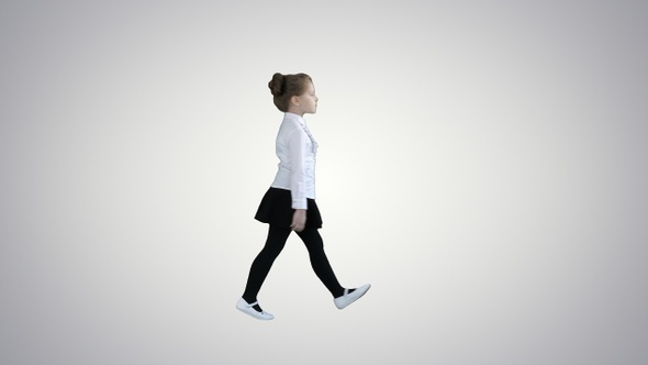 Little girl in school uniform walking by on gradient background