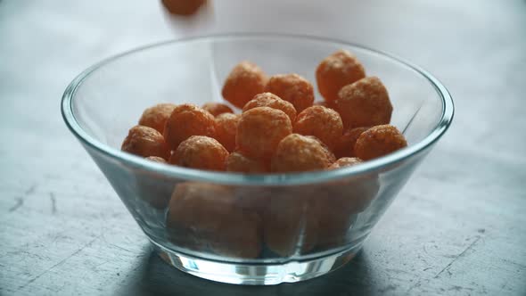 Cheese Balls Chips Is Poured Into A Glass Bowl In Super Slow Motion