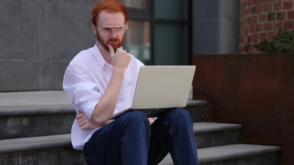 Pensive Designer Thinking while Working on Laptop Sitting on Stairs