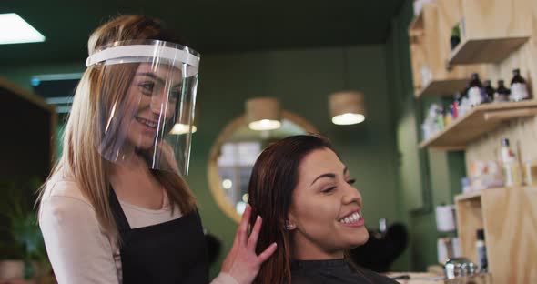 Female hairdresser running her fingers through hair of female customer