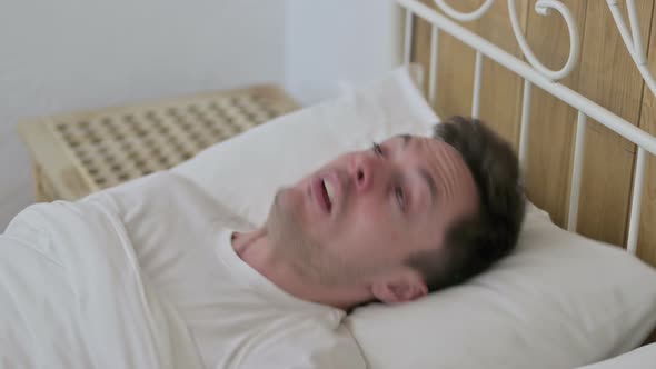 Scared Young Man Waking Up From Nightmare in Bed