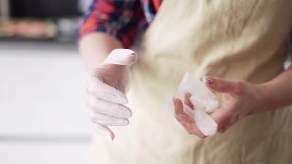 Woman Putting on Culinary Gloves on Kitchen Close Up