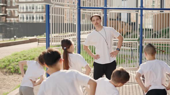 School Kids Do Exercise on Sport Class with Their Teacher Outdoor