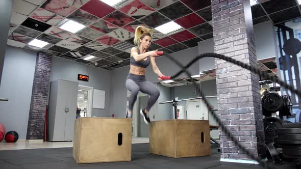 Young sporty woman working out with Fitness battling ropes at gym