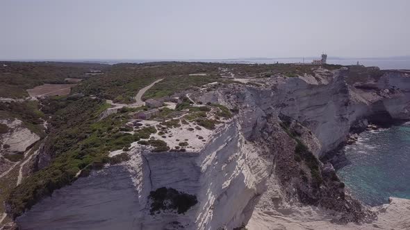 Aerial shoting in on lighthouse Phare de Pertusato, sitting on white coastal cliffs near Bonifacio