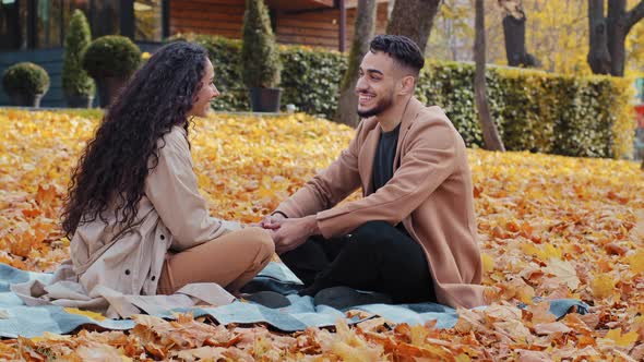Happy Cheerful Hispanic Couple on Date in Autumn Park Young Holding Hands Laughing and Smiling Sit