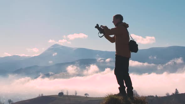 Silhouette of a Backpacker Photographer Taking Pictures of Morning Landscape in Autumn Mountains