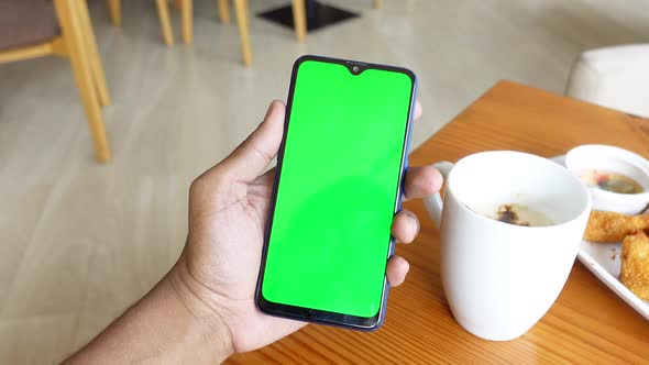 Young Man Hand Using Smart Phone with Tea and Cookies on Table