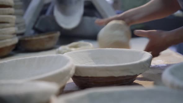 Bakers' Hands Kneading Forms of Dough on a Table for Bread Baking in a Molds