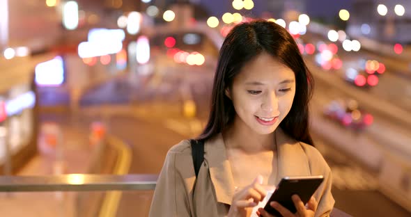 Woman sending message on cellphone in city at night