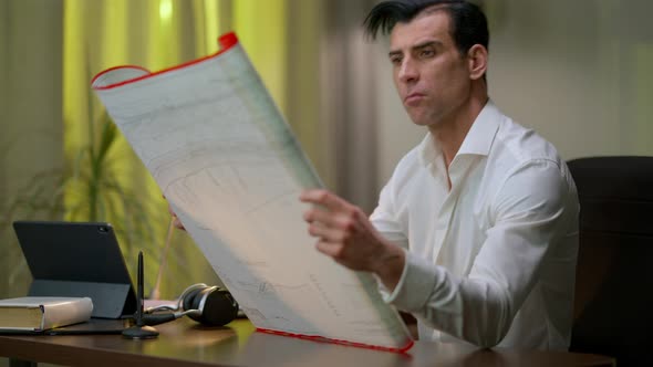 Focused Middle Eastern Man Examining Architectural Plan Thinking