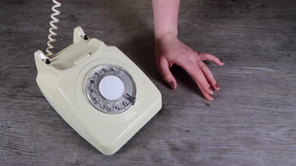 A elegant woman's hand picking up, putting down and flirting on an old vintage telephphone