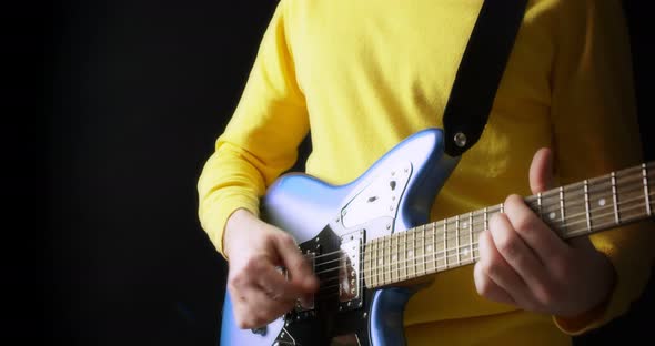 Male Guitarist in a Yellow Jumper Plays an Electric Guitar on Black Background