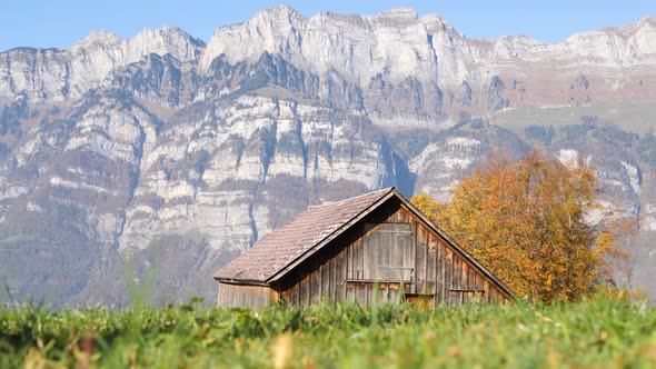Beautiful scenery with a shack and big mountains in the background.Camera rises from the ground.