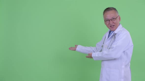 Happy Mature Japanese Man Doctor Presenting To the Back