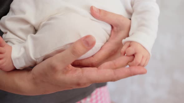 Closeup Small Hands of a Newborn Baby Hold Mom By the Finger