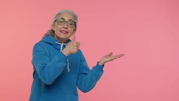 Mature Grandmother Showing Thumbs Up and Pointing Empty Place Advertising Area for Commercial Text