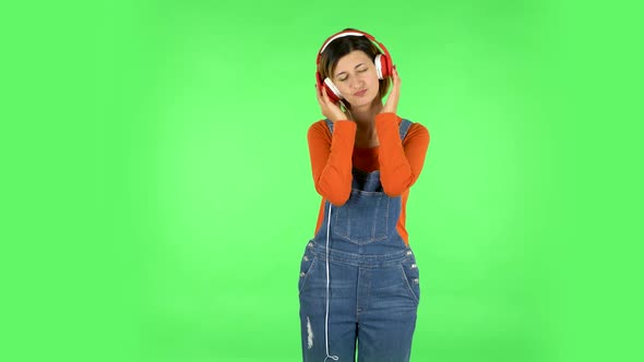 Cheerful Girl Dancing and Enjoys Music in Big Red Headphones. Green Screen