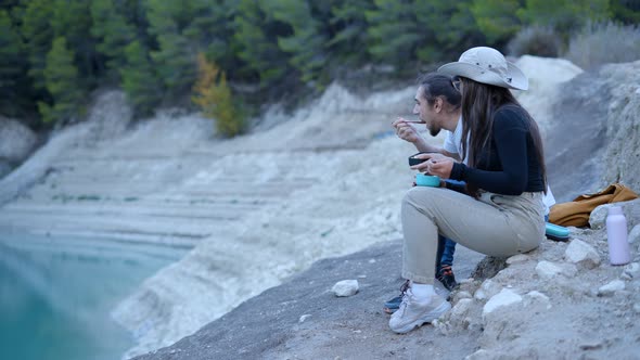 Static Side View of Young Couple Eating in Stony Nature on Hiking Trip