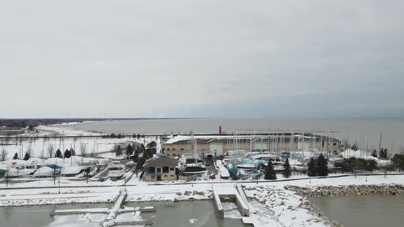 Drone view toward Lake Michigan with lighthouse and water tower in the distance in the winter.