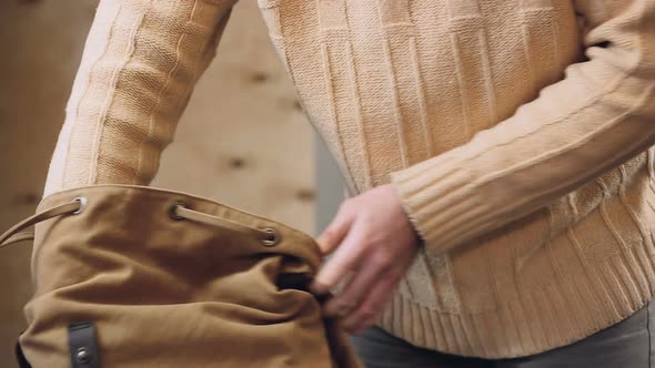 Furious Man Turning His Backpack Upside Down Searching for Necessary Thing