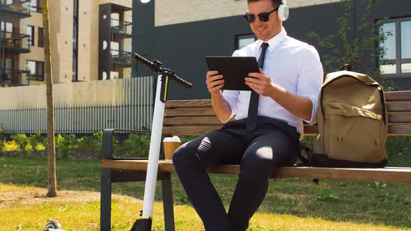 Businessman with Tablet Pc, Headphones and Scooter