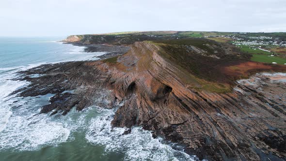 AERIAL: Wide circle of set of three caves and rocky coastline, Port Eynon, Gower, 4k Drone