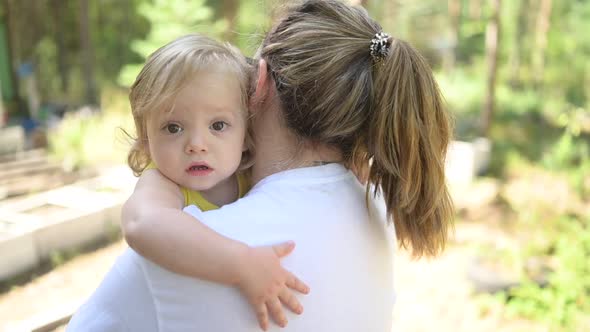 Little Cute Baby Toddler Girl Blonde with Curls on Mother's Arms