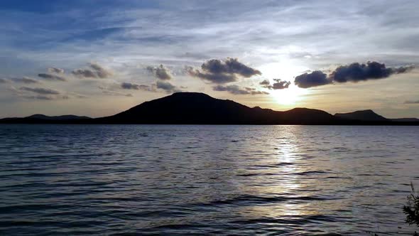 Beautiful sunset scenery with water, lake, clouds and sky. alt