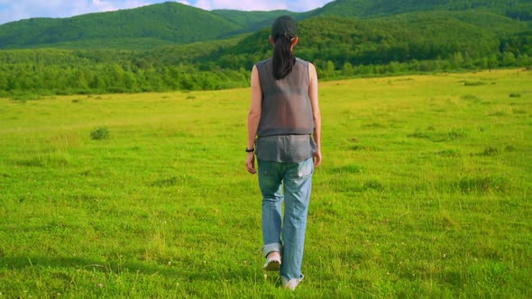 Back View Female Strolls on the Grass Countryside