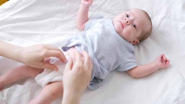 Mother Changes Diapers to Her Newborn Baby Little Boy on Changing Table in Clean Dry Nappy Mom