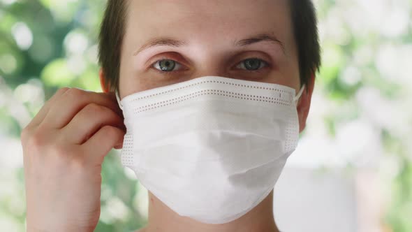 Female Woman with Wireless Headphones in a Medical Protective Mask Online Listening Music During