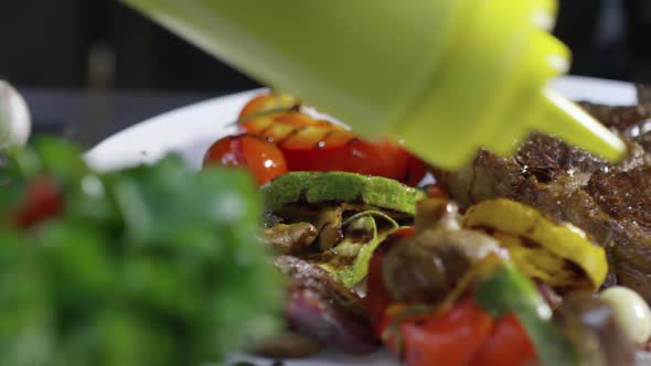 Adding Sauce to Beefsteak with Grilled Vegetables