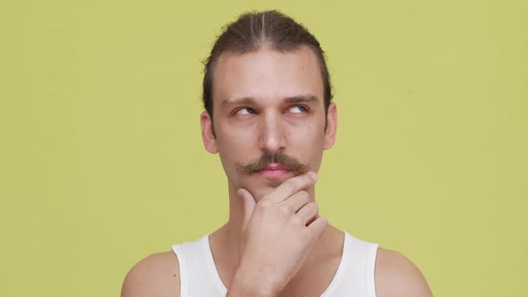 Closeup Brooding Man in Shirt Touching His Chin Over Yellow Background Concept of Emotions