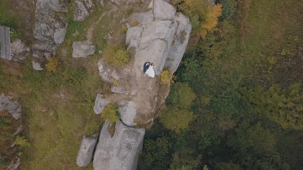 Newlyweds Stand on a High Slope of the Mountain. Groom and Bride. Aerial View