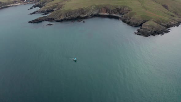 Drone flight over a boat in clear green seawater