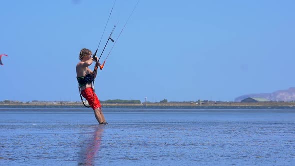 A man kiteboarding and doing a jumping trick on a kite board.