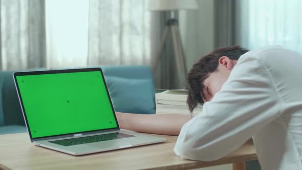 Close Up Of Asian Man Student Being Sleepy While Looking At Green Screen Computer At Home