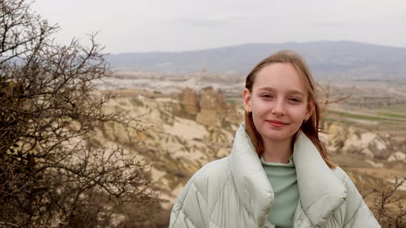 Portrait Smiling Young Woman at Windy Mountain Looking to Camera