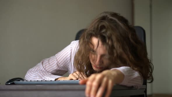 Tired Young Woman with Curly Hair and White Shirt is Working at the Office Using Her Laptop Routine