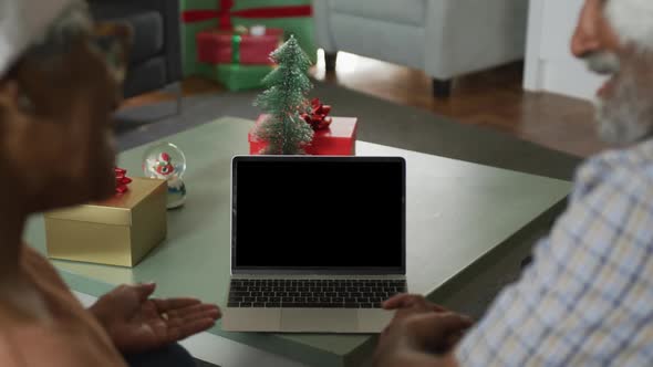 Animation of african american senior couple using laptop with copy space on screen at christmas time