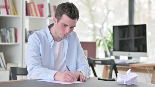 Upset Young Man Writing Documents Doing Paperwork
