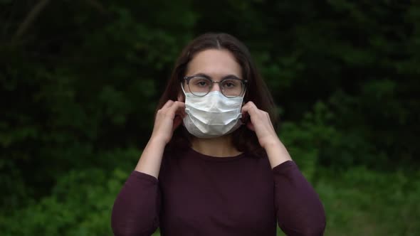 A Young Woman with Glasses Takes Off a Medical Mask and Throws It at the Camera